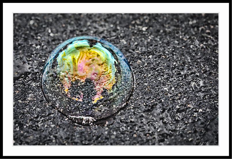 Girl in a bubble jon the ground after a recent rain.